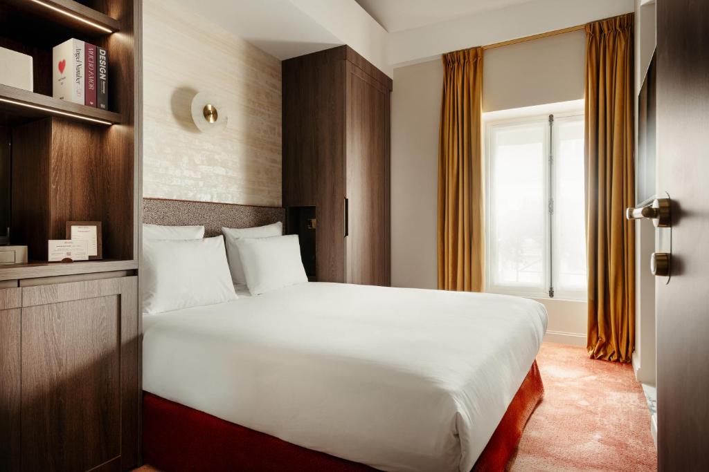 a bedroom with a large white bed and a window at Jills Hôtel in Paris