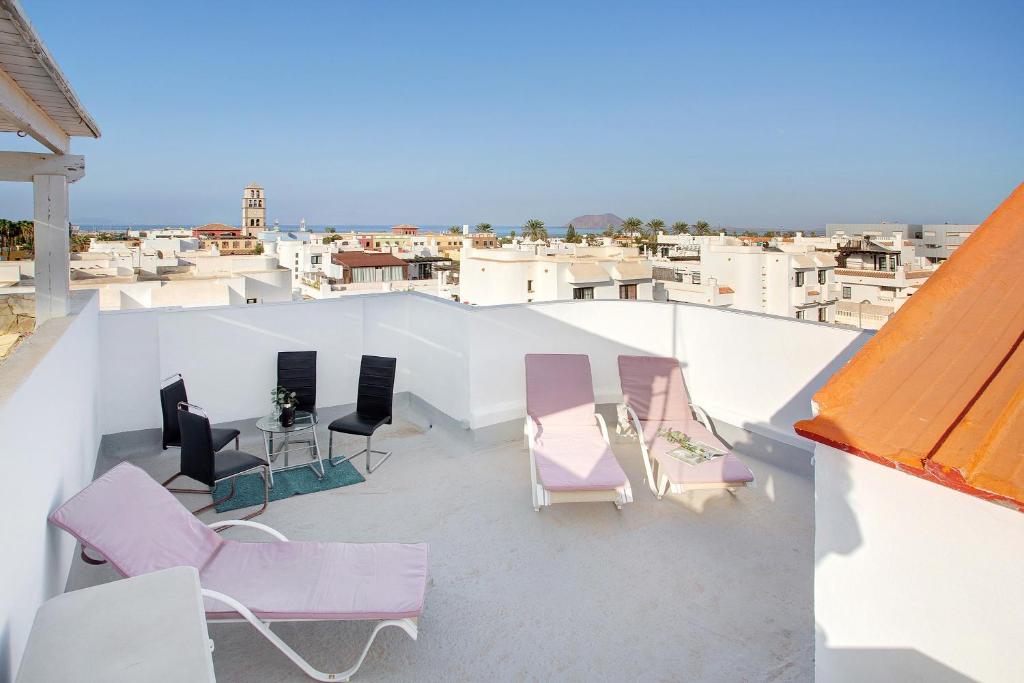 a balcony with chairs and tables on a roof at Casa del Sol Rosa in Corralejo