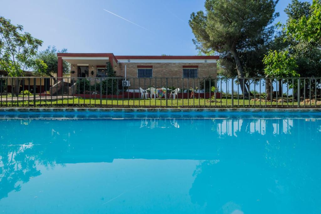a large blue swimming pool with a house in the background at Villa Manolita in Carmona