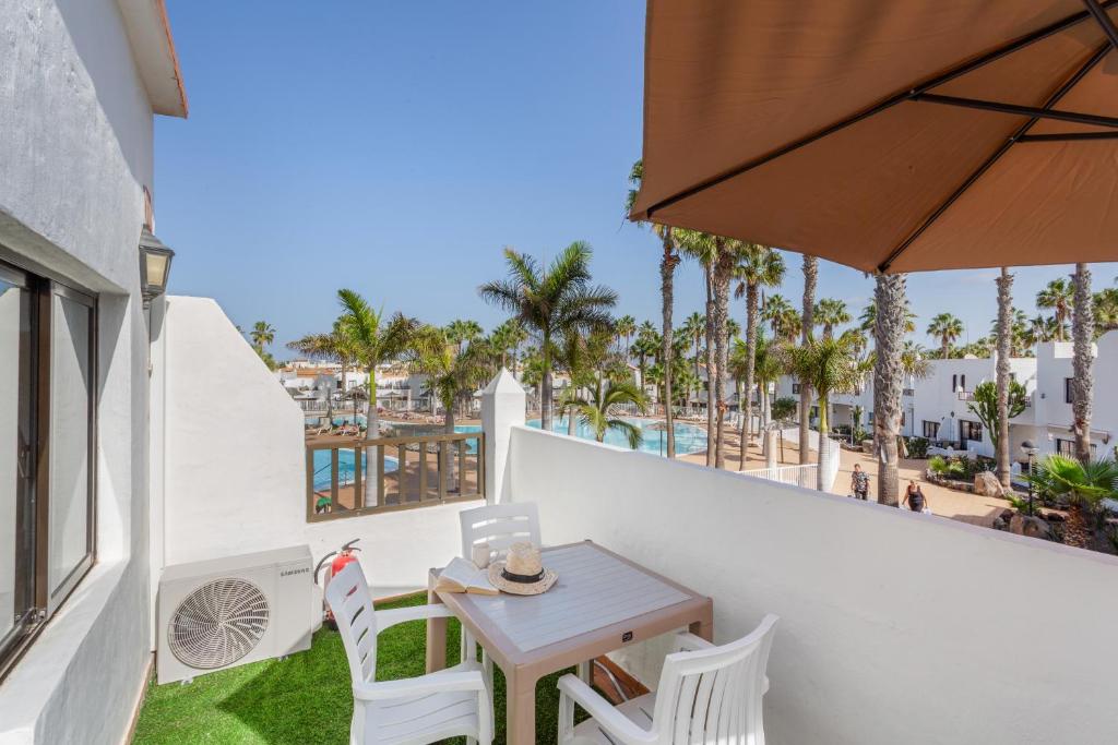 a table and chairs on a balcony with palm trees at Brisa Azul in Corralejo