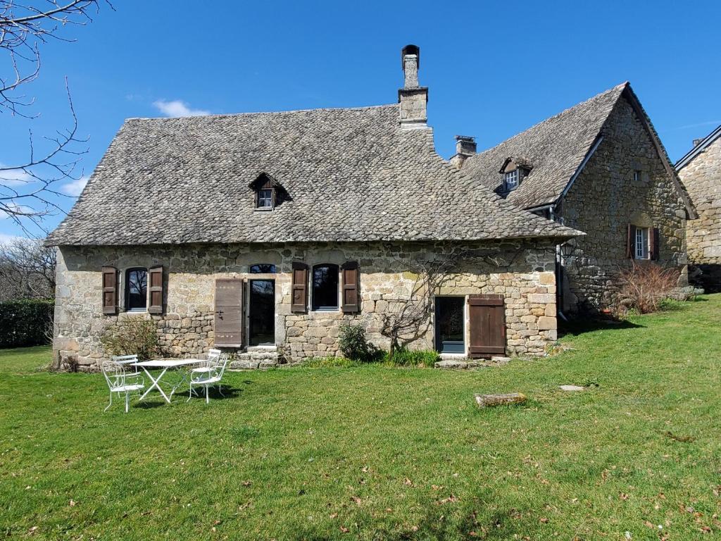 an old stone house with a table in the yard at Maison de Vacances Chadirac in Auriac