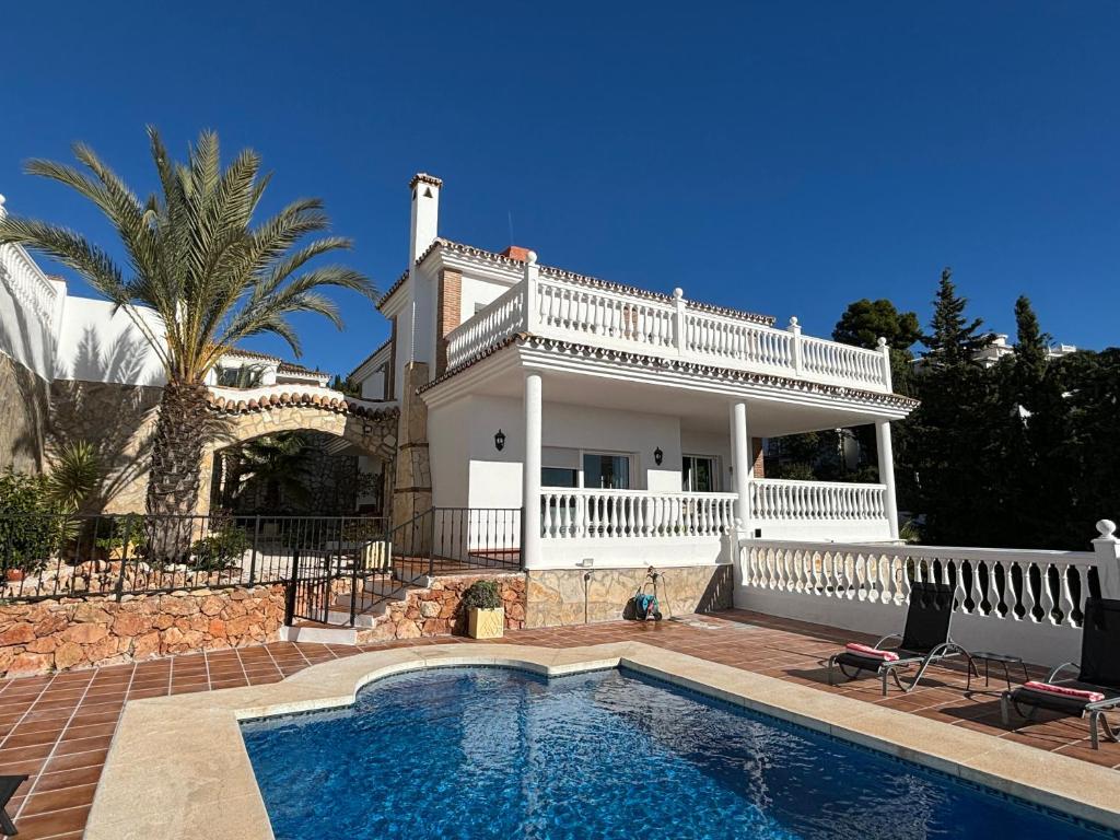 a villa with a swimming pool in front of a house at Casa Montelado in Mijas