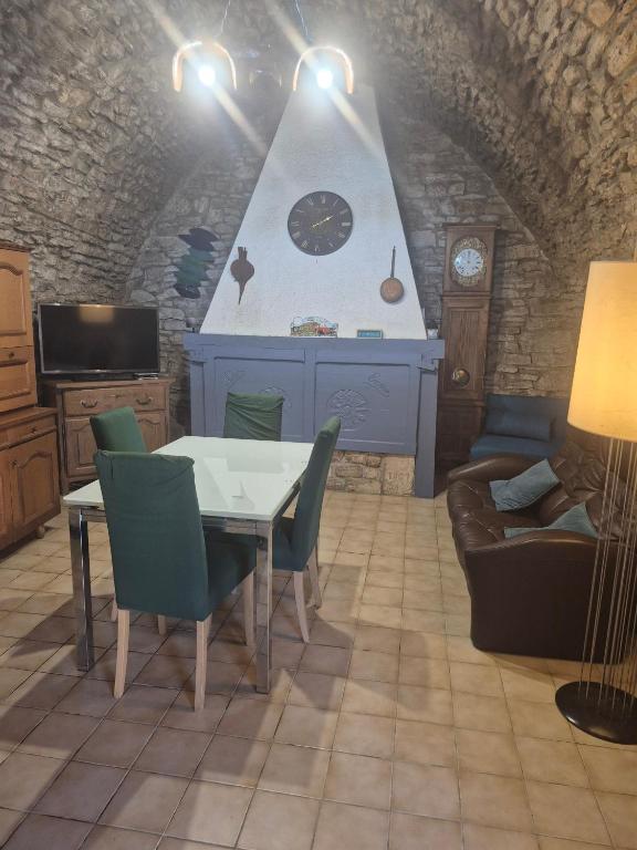 a living room with a table and a clock on the wall at Gîte Du Recoux in Le Recoux