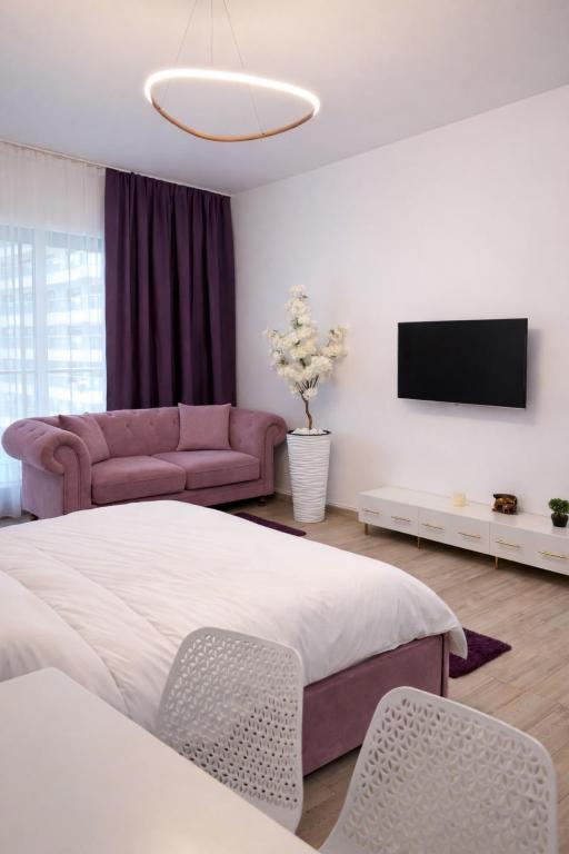 a bedroom with a bed and a couch and a tv at Ametist in Mamaia