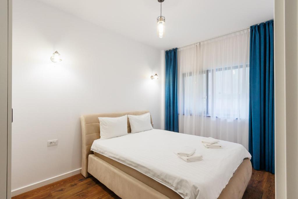 a bedroom with a bed and a window with blue curtains at Confort Apartment in Iaşi