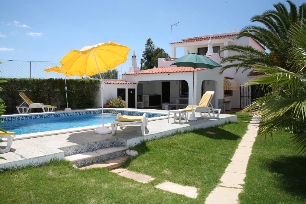 a pool with chairs and umbrellas next to a house at Quinta da Eira in Lagoa