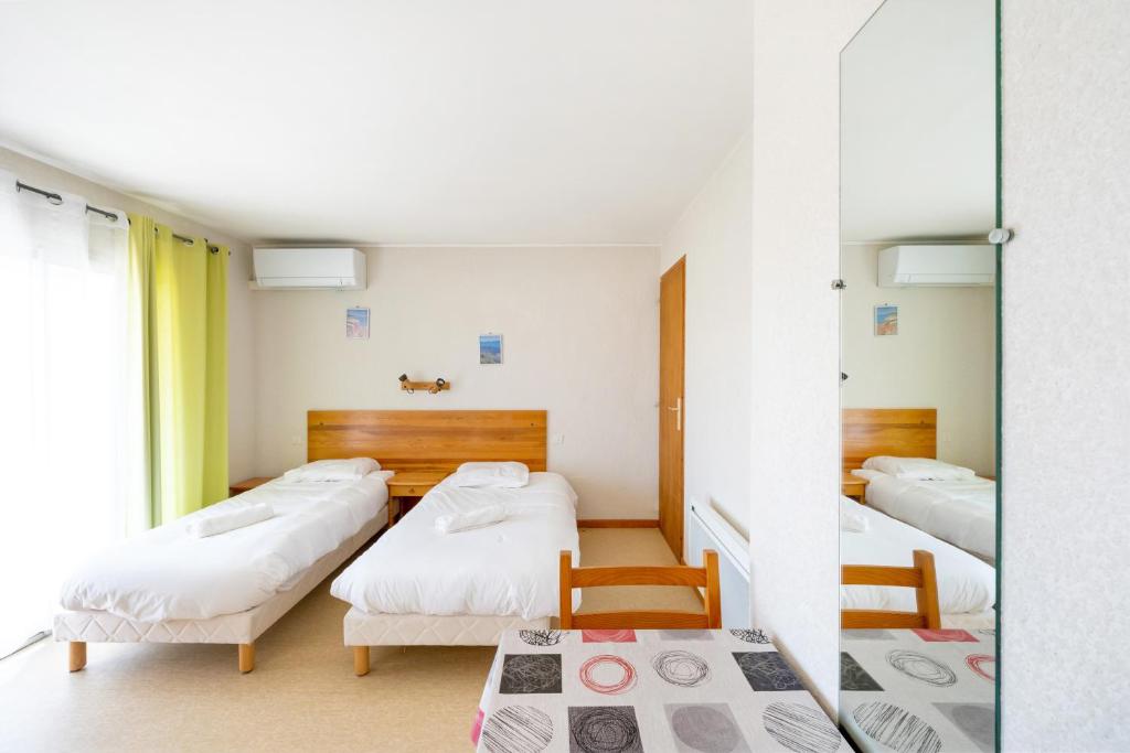 a room with three beds and a window at Les Mimosas - Appartement 07 in Cazaubon