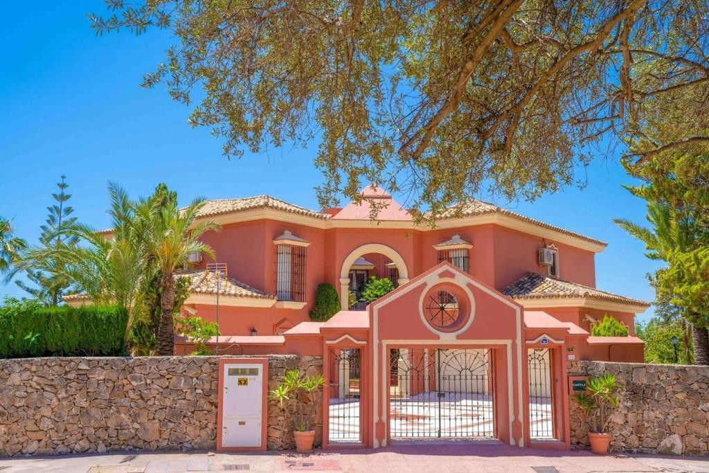 a large pink house with a gate and a fence at vituco34 in Mijas