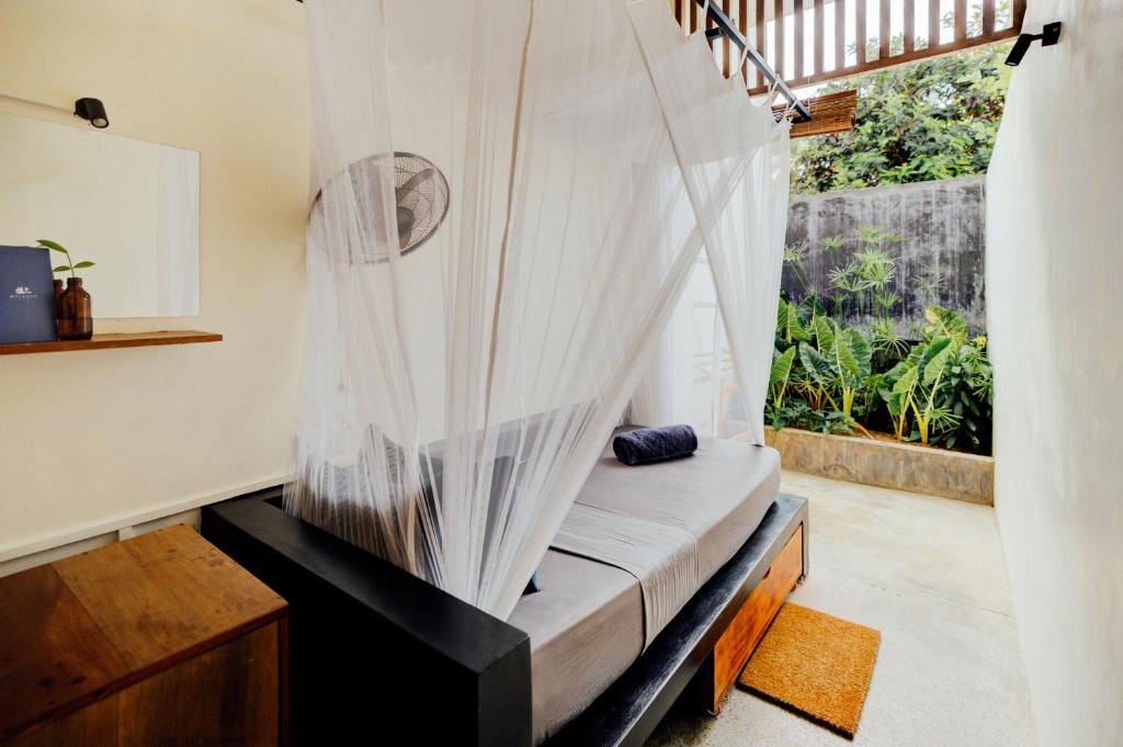 a bed with mosquito netting in a room with a window at Malkoha Studios in Dickwella