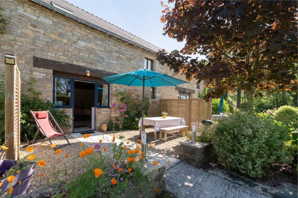a patio with a table and a blue umbrella at Domaine de Lestroué - Île de Groix in La Vraie-Croix