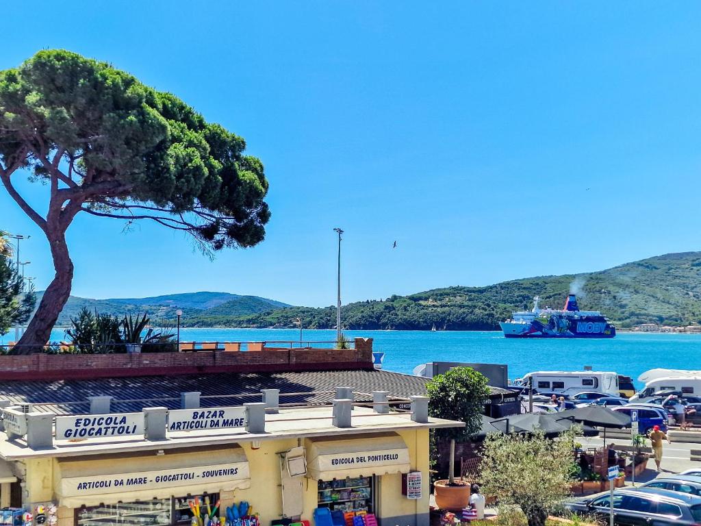 a harbor with a tree and a boat in the water at Casa Caterina in Portoferraio