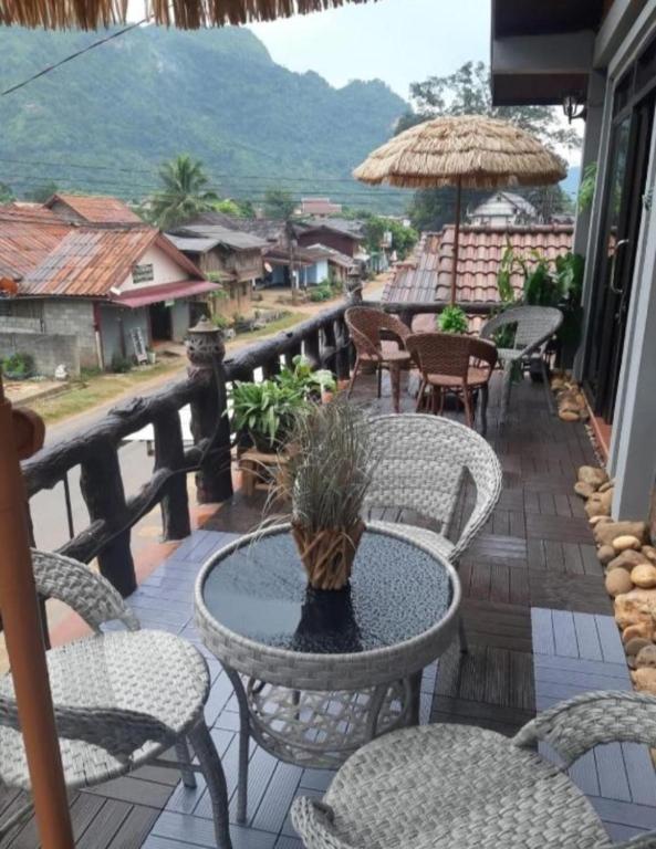 a patio with chairs and a table and an umbrella at Vinla Guesthouse & Backpackers Hostel in Nongkhiaw