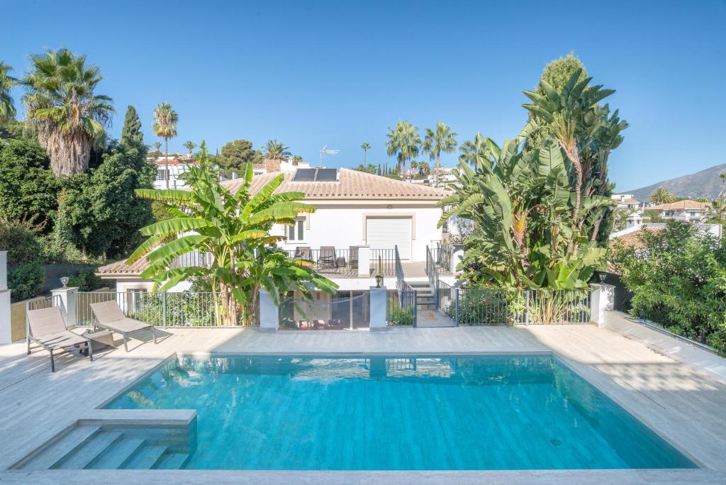 a swimming pool in a villa with palm trees at Villa Jazmin in Mijas Costa