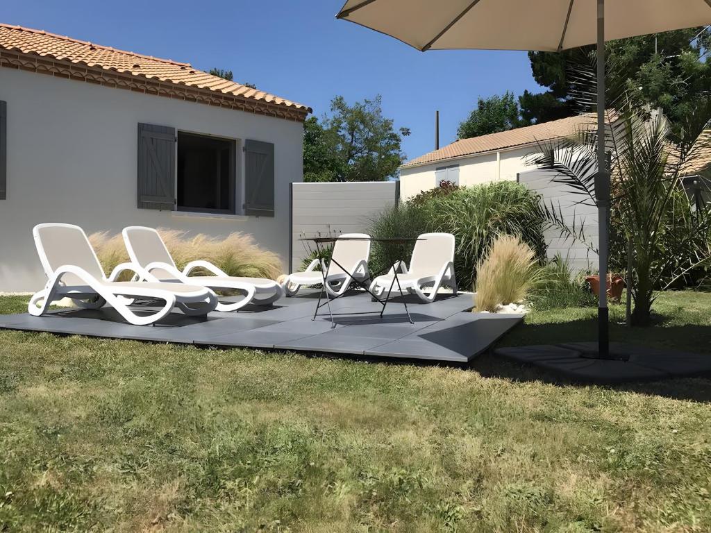 a group of chairs and an umbrella on a patio at Le Nid Marin - 76 in Pornic