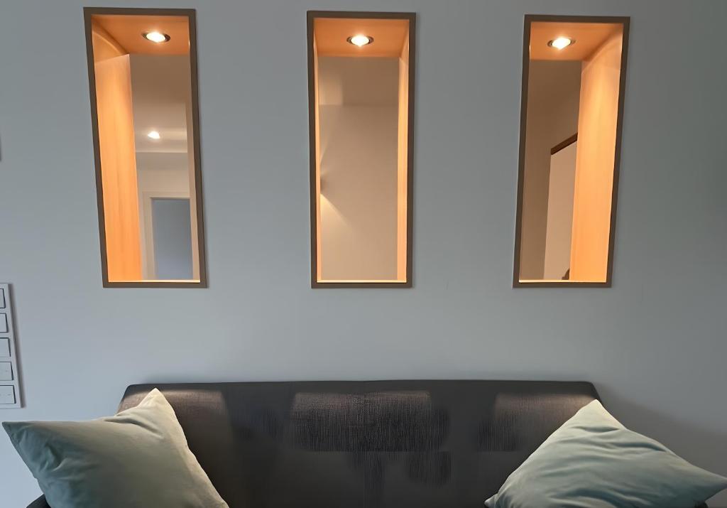 three mirrors on a white wall with a couch at Ferienwohnung am Rotmannsweg in Marbach am Neckar