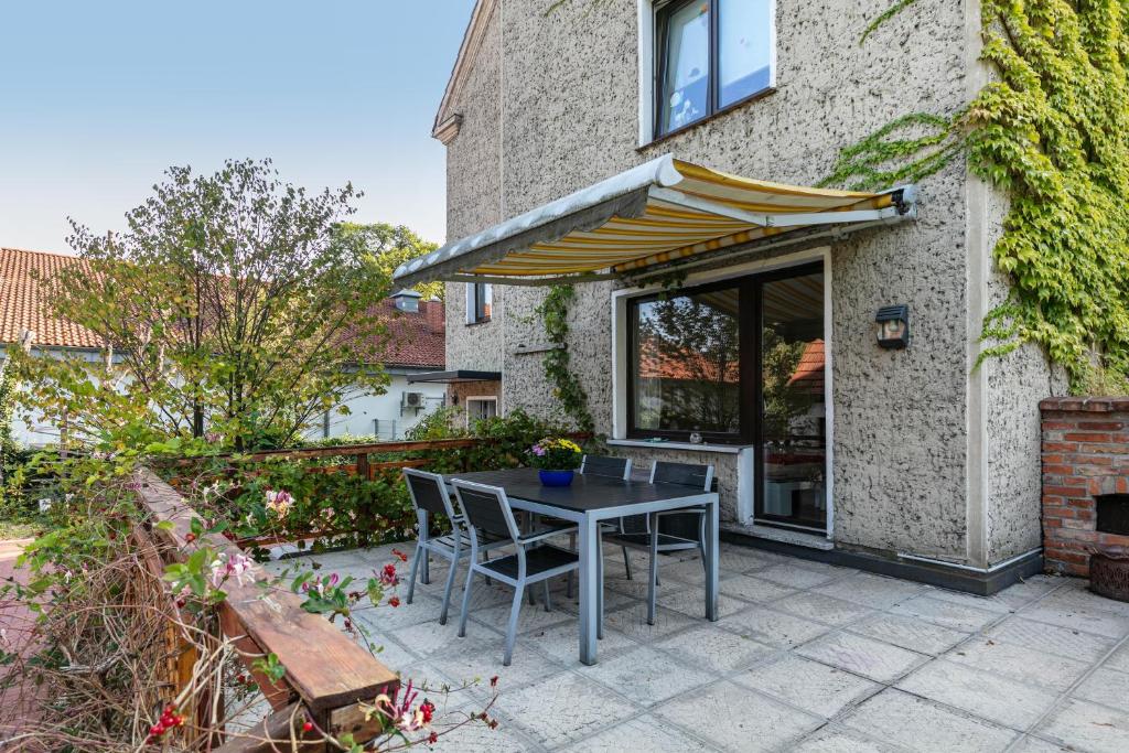 a patio with a table and chairs and an umbrella at Ferienwohnung Am Straussee in Strausberg