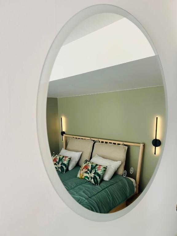 a mirror reflecting a bed with pillows on it at Between hills and home in Trooz