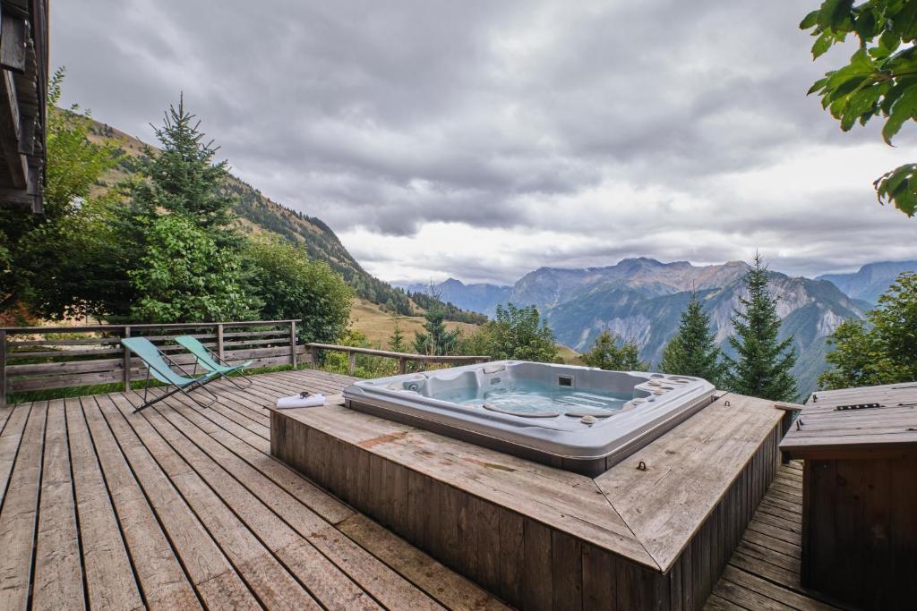 a hot tub sitting on top of a wooden deck at Chalet il fera beau demain in Villard-Reculas