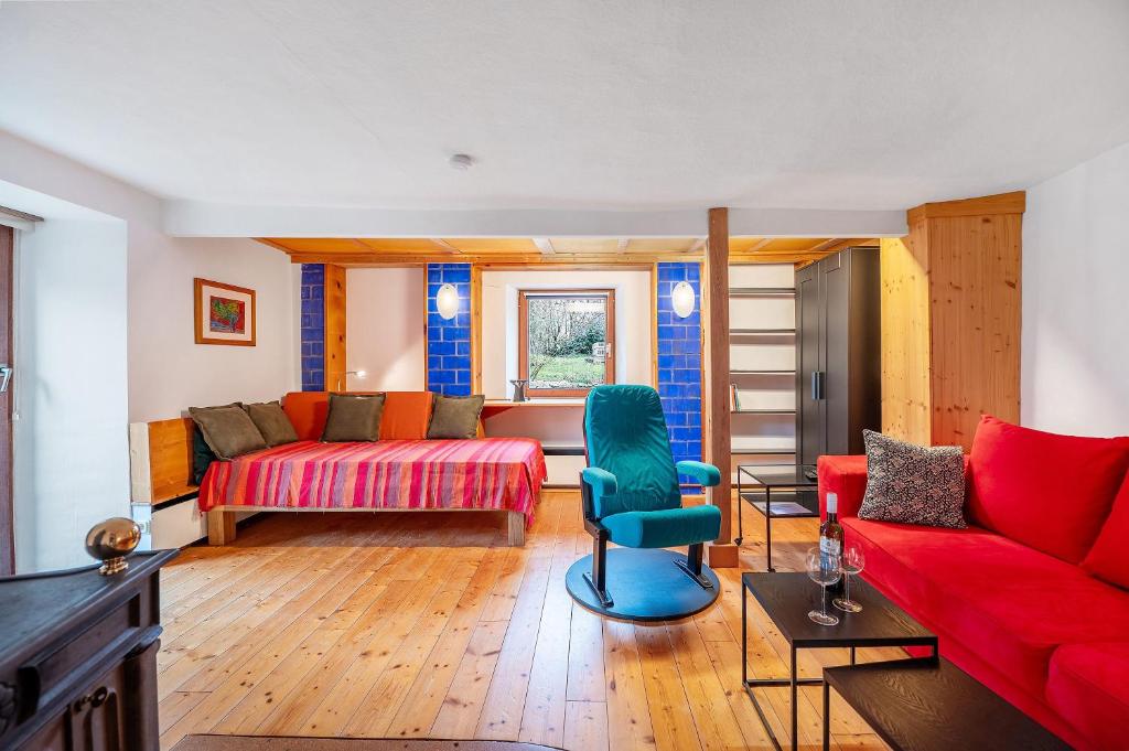a living room with a red couch and a blue chair at Ferienwohnung Kaleidoskope in Buhlenberg