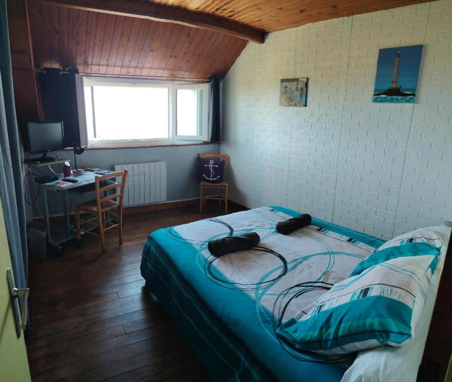 a bedroom with a bed and a desk and a window at Chambre phare in Auderville