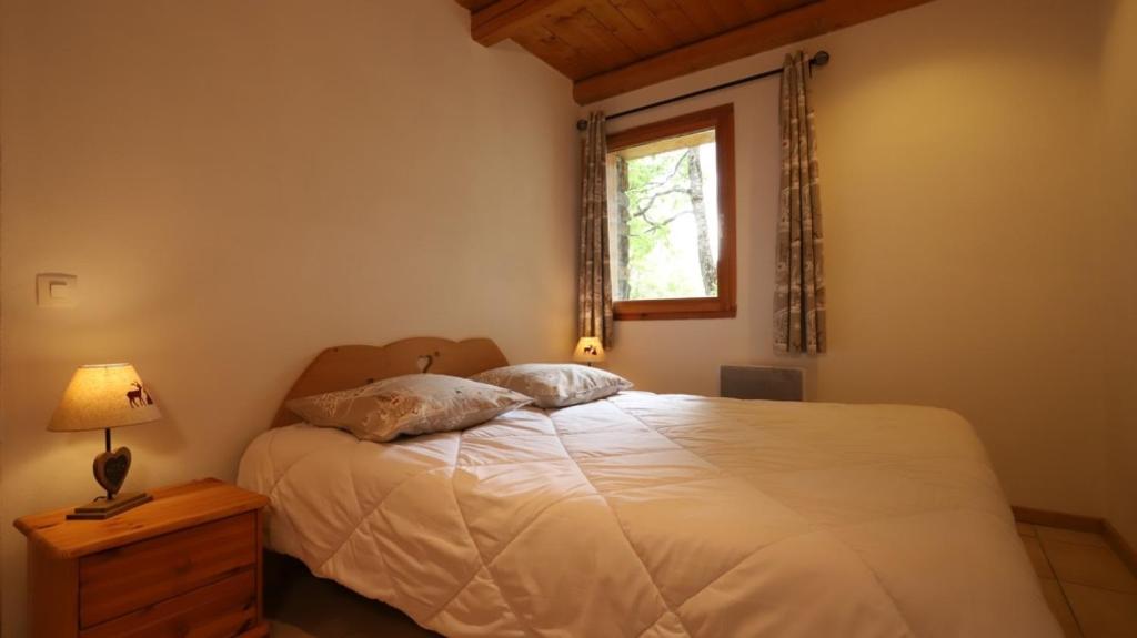 a bedroom with a bed with a lamp and a window at Chalet Alpaga 6 in Bonneval-sur-Arc