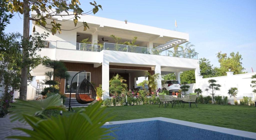 a white house with a patio and a yard at Kaashi Flora Whitehouse-9BHK in Varanasi