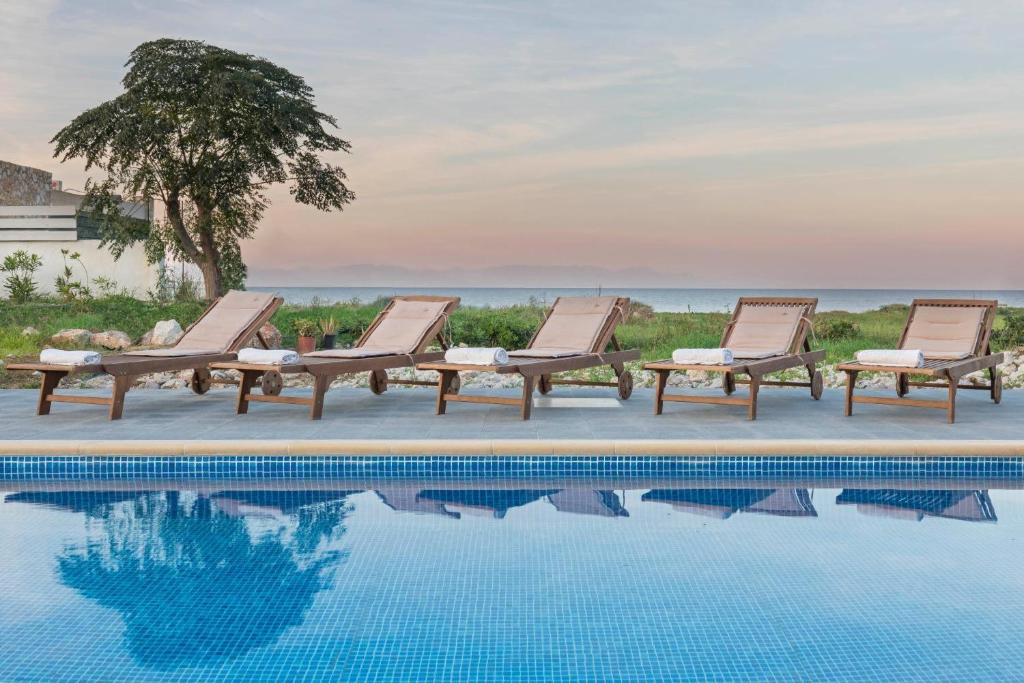 a group of lounge chairs next to a swimming pool at Rhodes Sea Villas No 2 in Ialysos