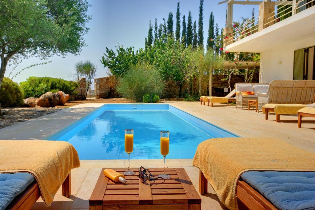 a pool in a backyard with two beds and two candles at Villa Telina Ideales Resort in Kefallonia
