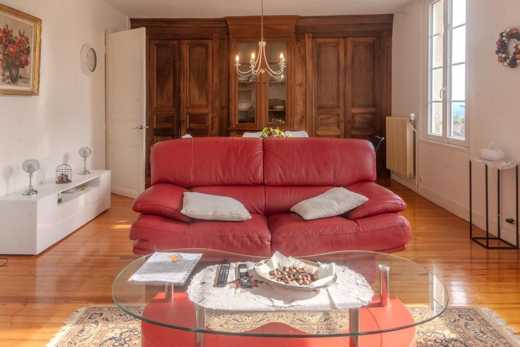 a red couch in a living room with a glass table at Les Hirondelles Archiac in Archiac