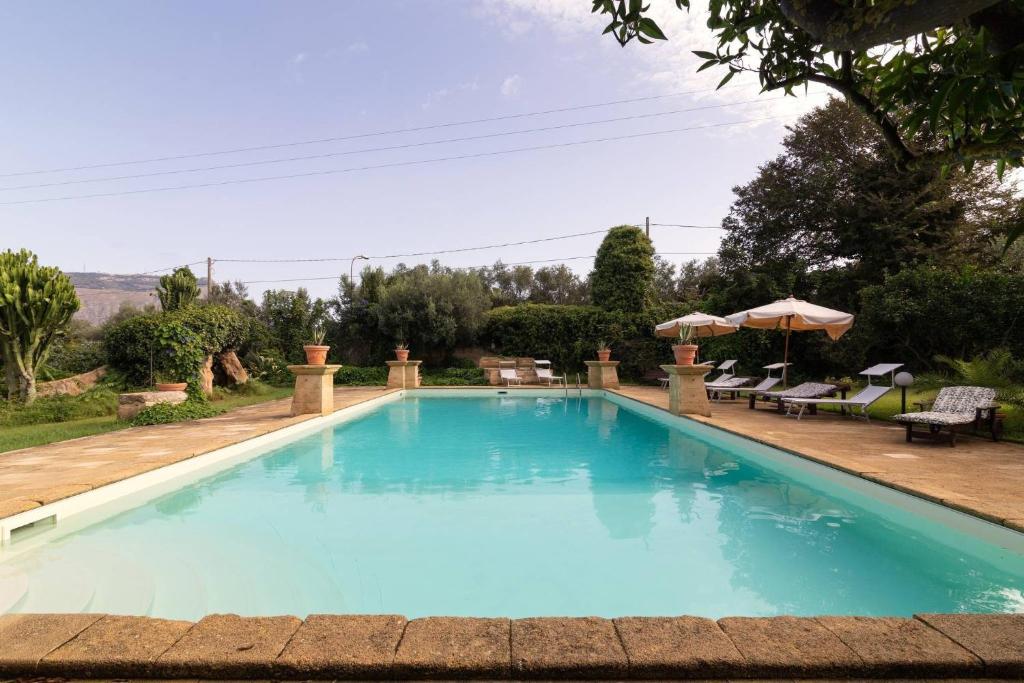 a large blue swimming pool with chairs and umbrellas at Tenuta Donna Vittoria in Trapani