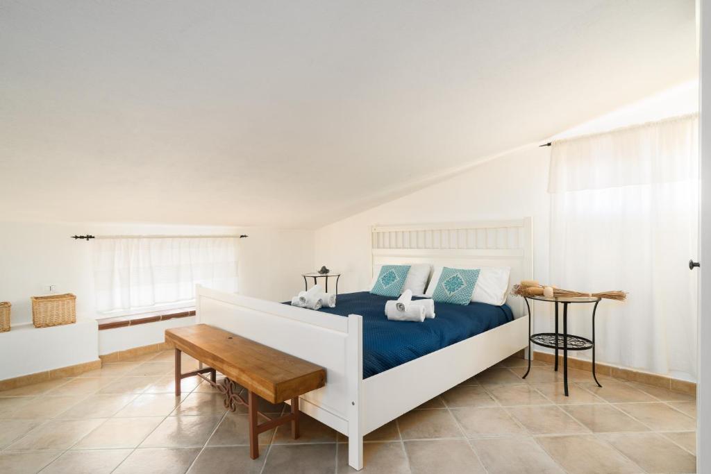 a bedroom with a white bed and a wooden table at Giojas125 Monolocale per 4 persone in Orosei