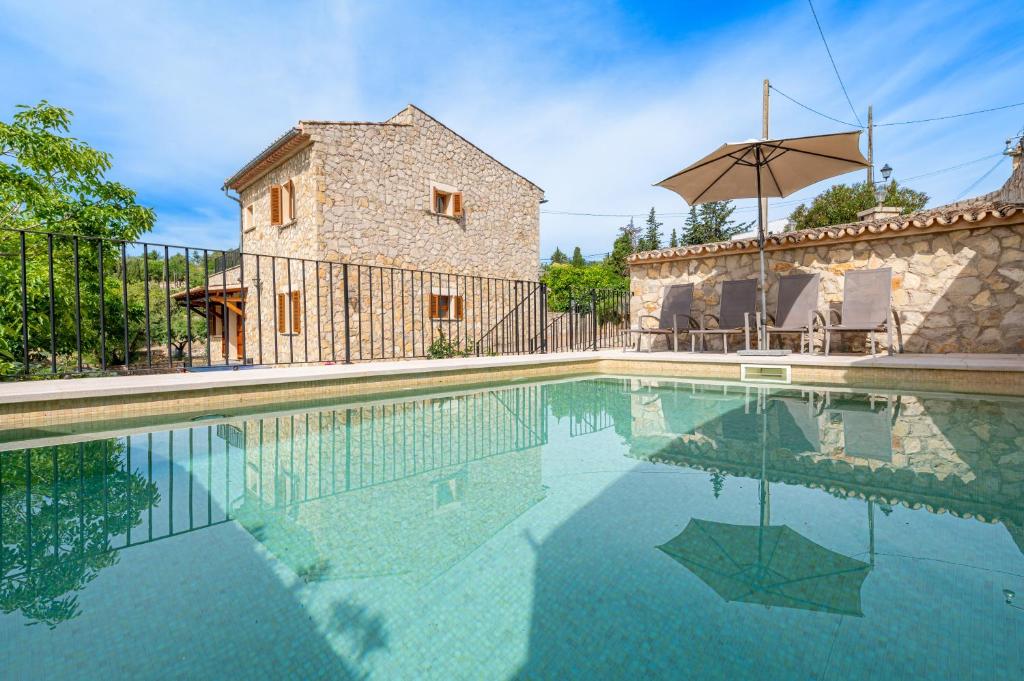 a pool in front of a house with an umbrella at Son Sant Joan in Alaró