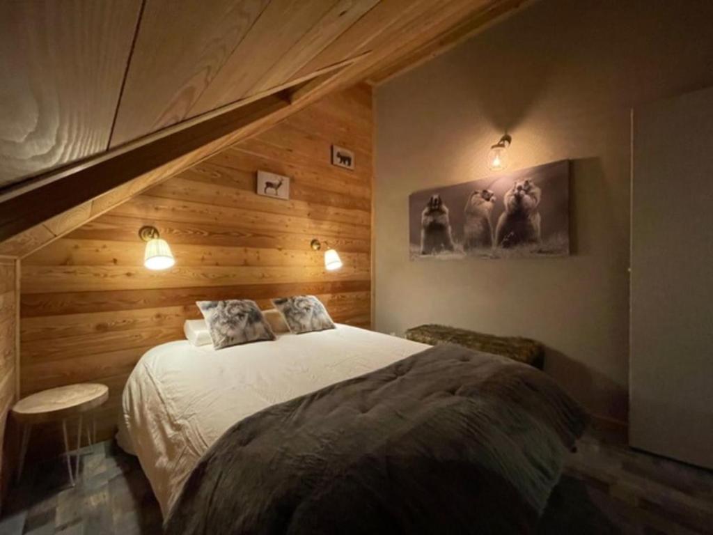a bedroom with a bed and a wooden wall at Chez nous piste noire in Briançon