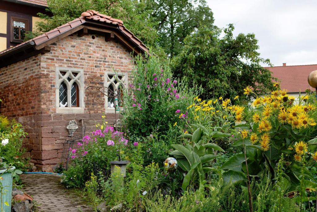 a garden with flowers and a brick building at Ferienwohnung-Cottage Rhöner Kräute in Buttlar