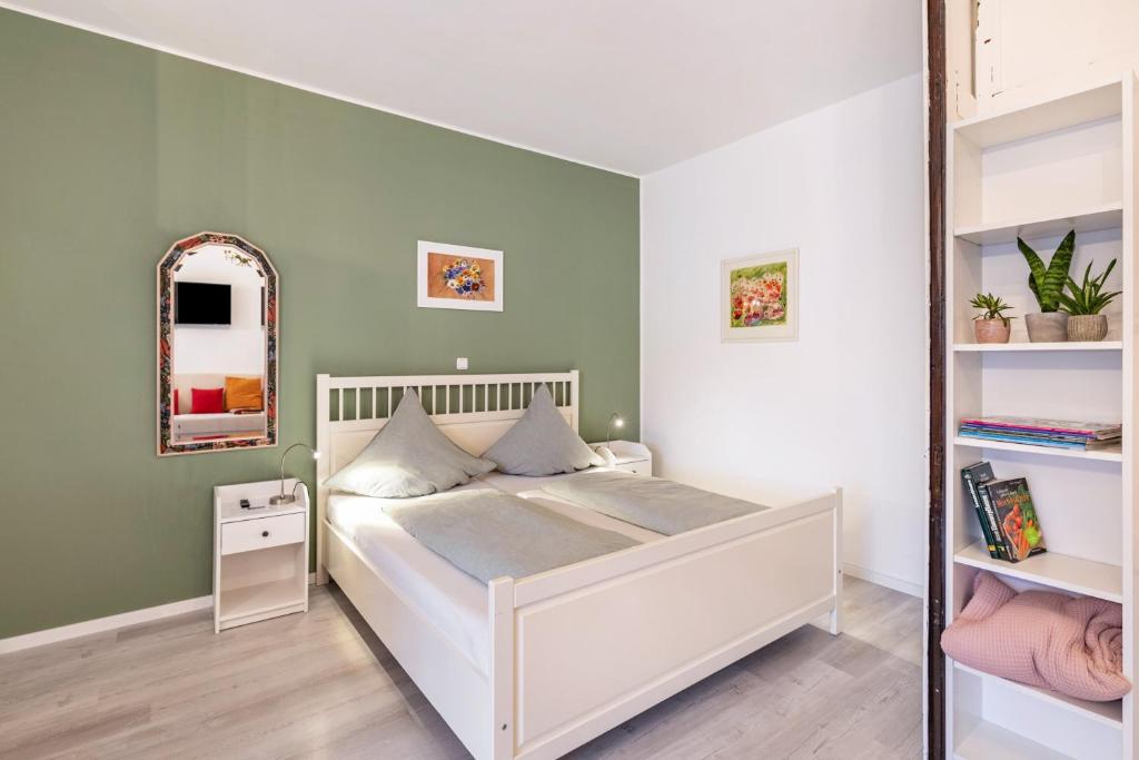 a bedroom with a white bed and a mirror at Garten Apartment in Kerken