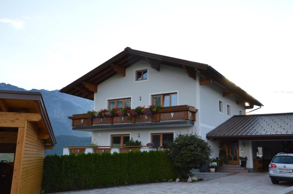 a white house with a balcony with flowers on it at Ferienwohnung Lienbacher in Abtenau