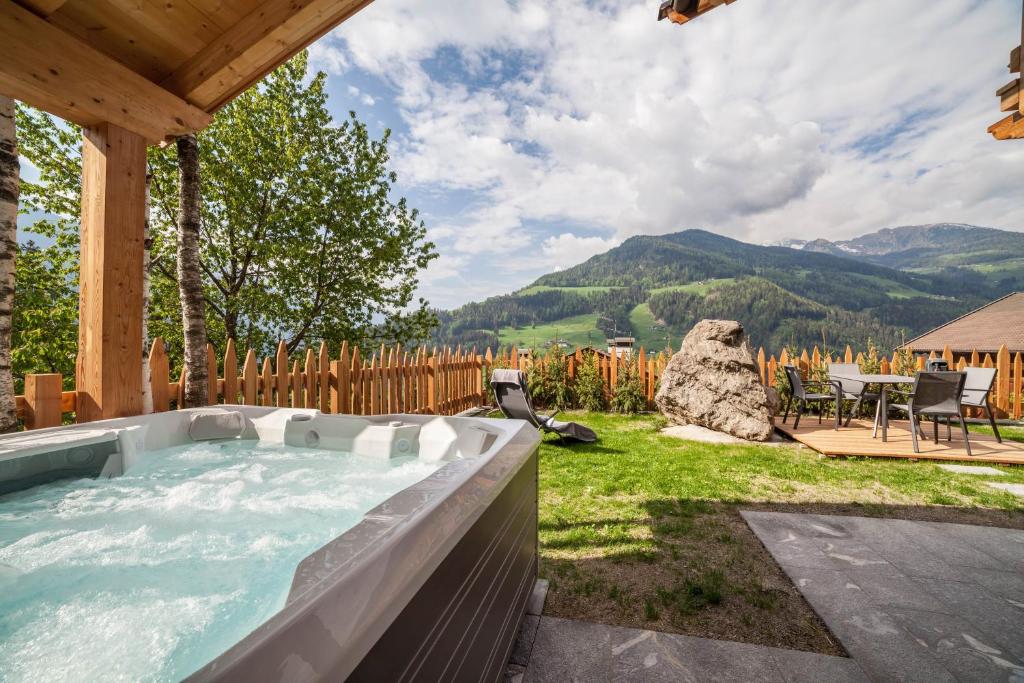 a hot tub in a backyard with a table and chairs at Bergchalet Heidi und Peter in San Leonardo in Passiria