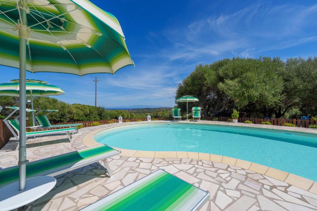 a large swimming pool with an umbrella and two chairs at Casa Mirto con piscina e vista mare in Aglientu