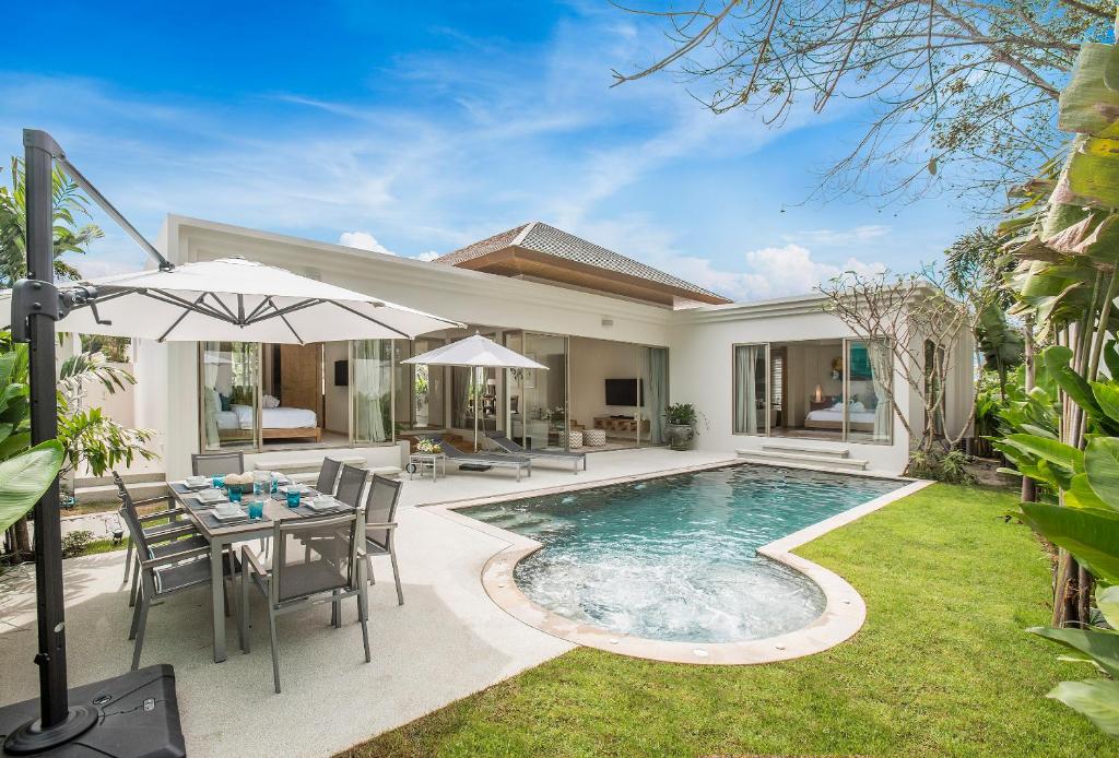 a backyard with a pool and a table and an umbrella at Villa 777 Phuket Private Pool Villa in Bang Tao Beach