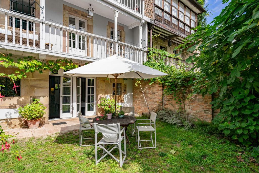 a table with an umbrella in the yard of a house at Apartamento 1 Casa Las Indianas in Selores