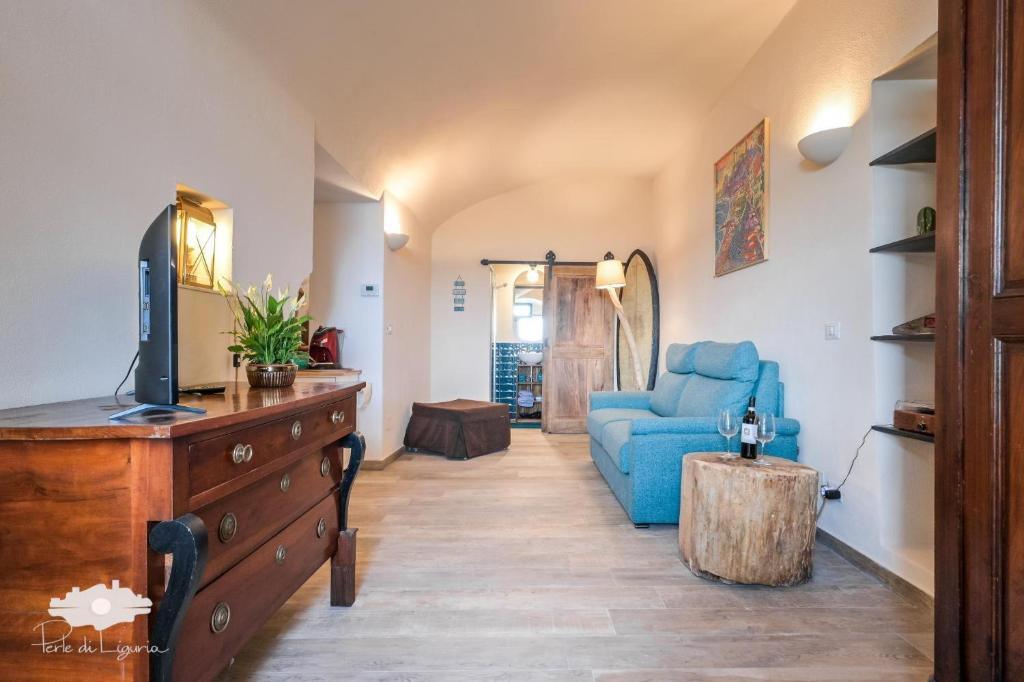 a living room with a blue couch and a tv at Pieds Dans L'eau - Bogliasco in Bogliasco