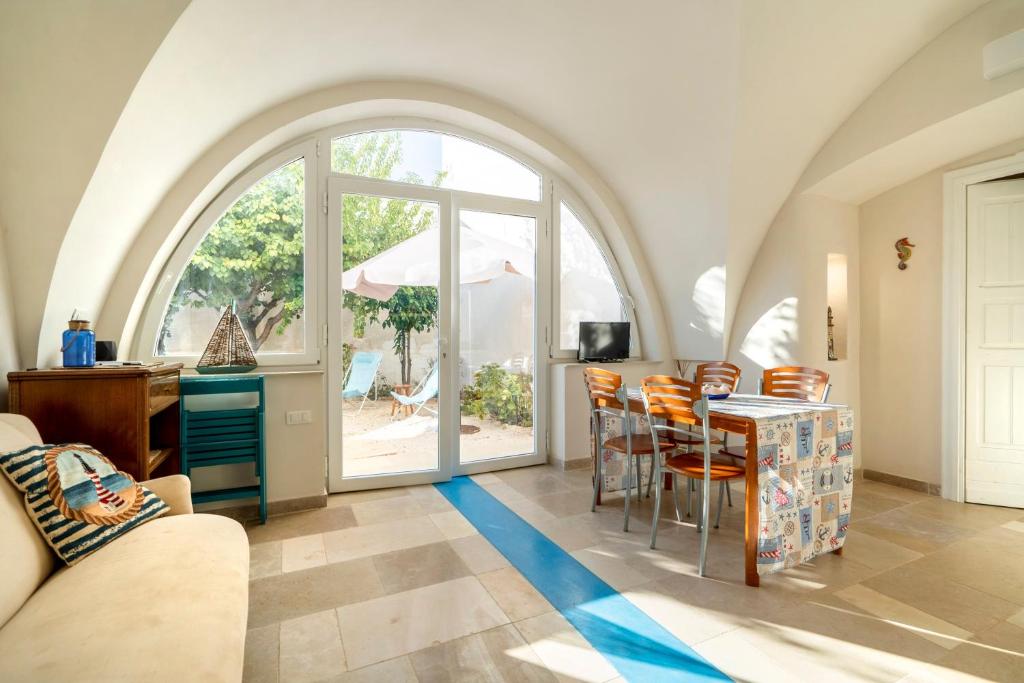 a living room with an arched window and a table and chairs at Agrumeto sul mare in Ostuni