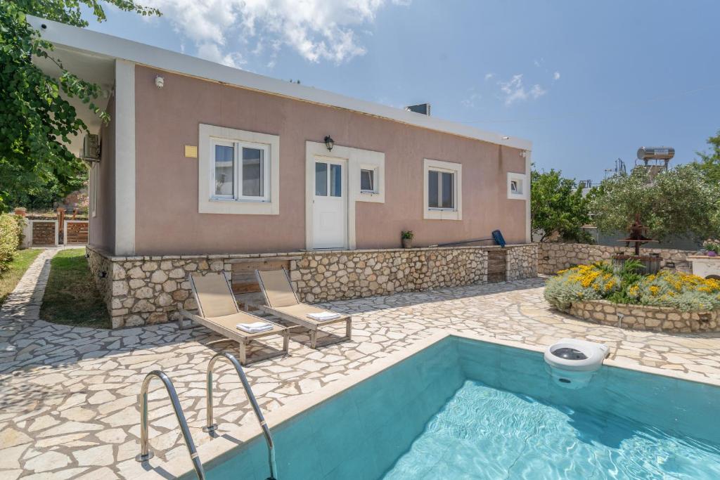 a villa with a swimming pool in front of a house at Stathis Home in Exanthia