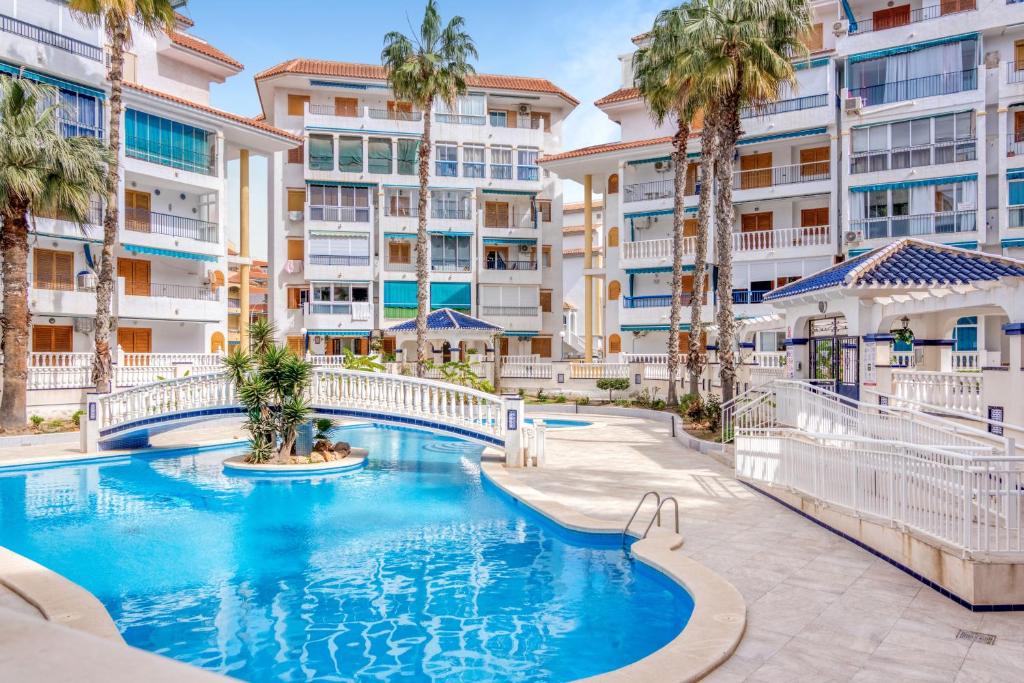 a swimming pool with palm trees in front of a building at Sueño in La Mata