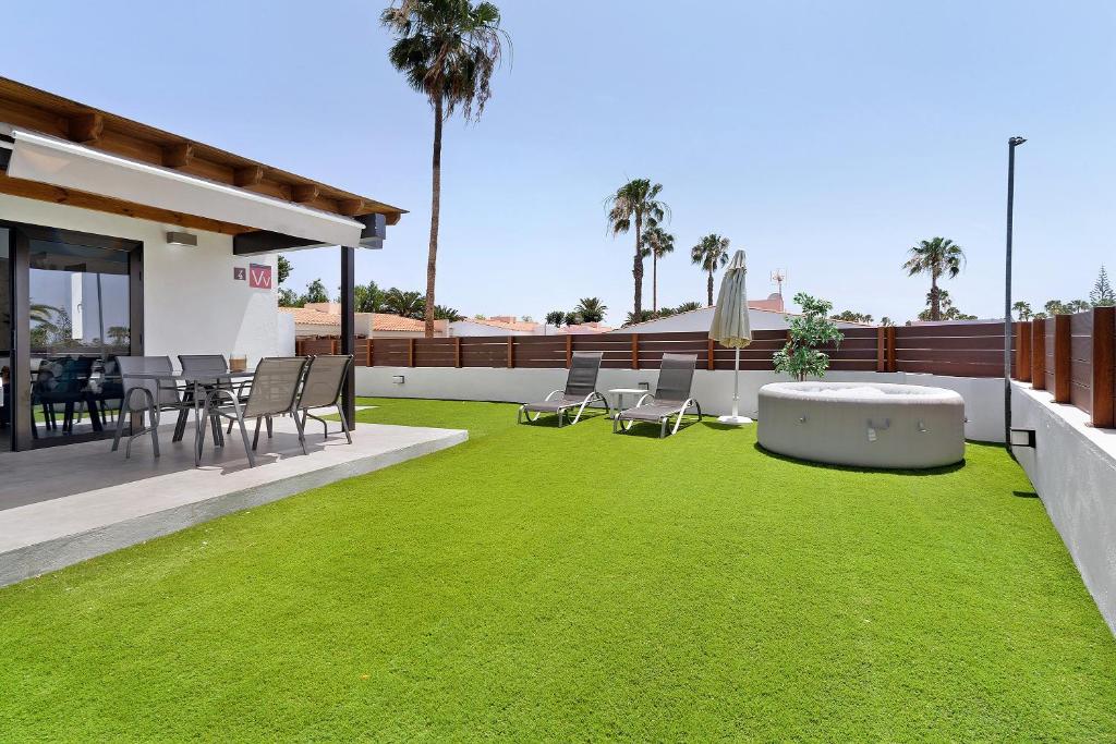 a patio with green grass and a table and chairs at Casa Luna Kingbed and Jacuzzi in Maspalomas
