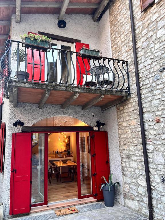 a building with red doors and a balcony with umbrellas at Casa Storica Gardola in Tignale