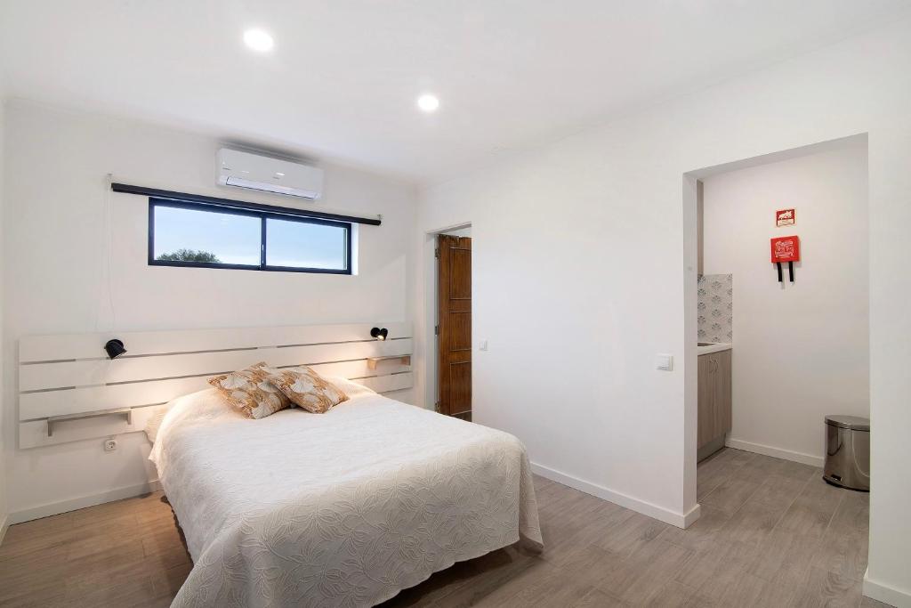 a white bedroom with a bed and a window at Apartamento nº2 - Seashel in Moncarapacho