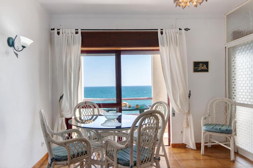 a dining room with a table and chairs and the ocean at Beachfront Apartment T2 in Quarteira