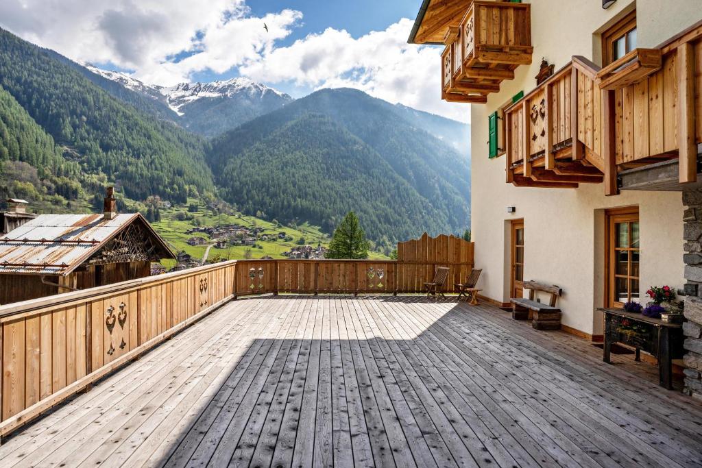 a large wooden deck with mountains in the background at La Chiasa in Rabbi