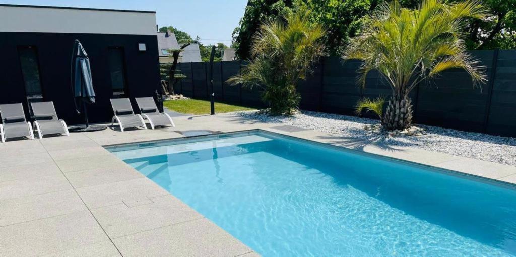 a blue swimming pool with two chairs and a fence at Villa de standing piscine 10 pers in Bruz